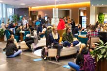 Michigan students gathered in a lobby/snack area talking and using devices.