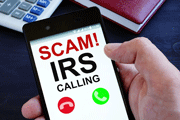 Hand holding phone that reads, SCAM! IRS CALLING