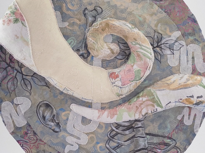 Side angle of a circular fabric sculpture featuring abstract shapes, and fragmented organic shapes arranged in layers across the art piece.